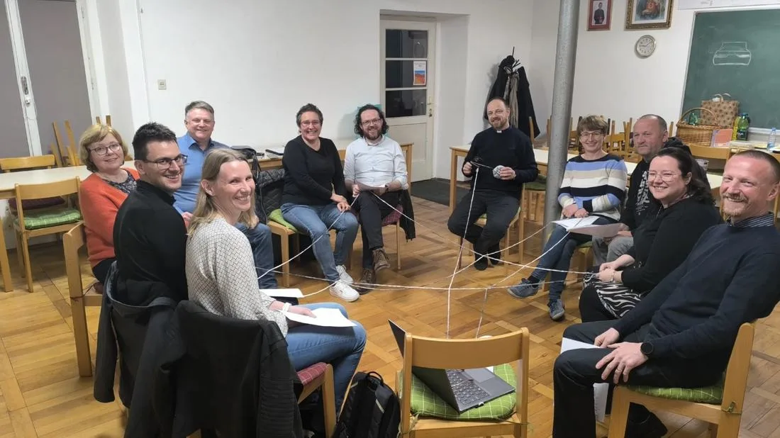 A marriage group of couples and a priest sitting in a circle during a monthly meeting